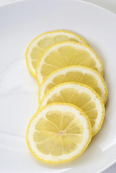 Zitronen Fünf dünne Zitronenscheiben auf einem weißen Teller.